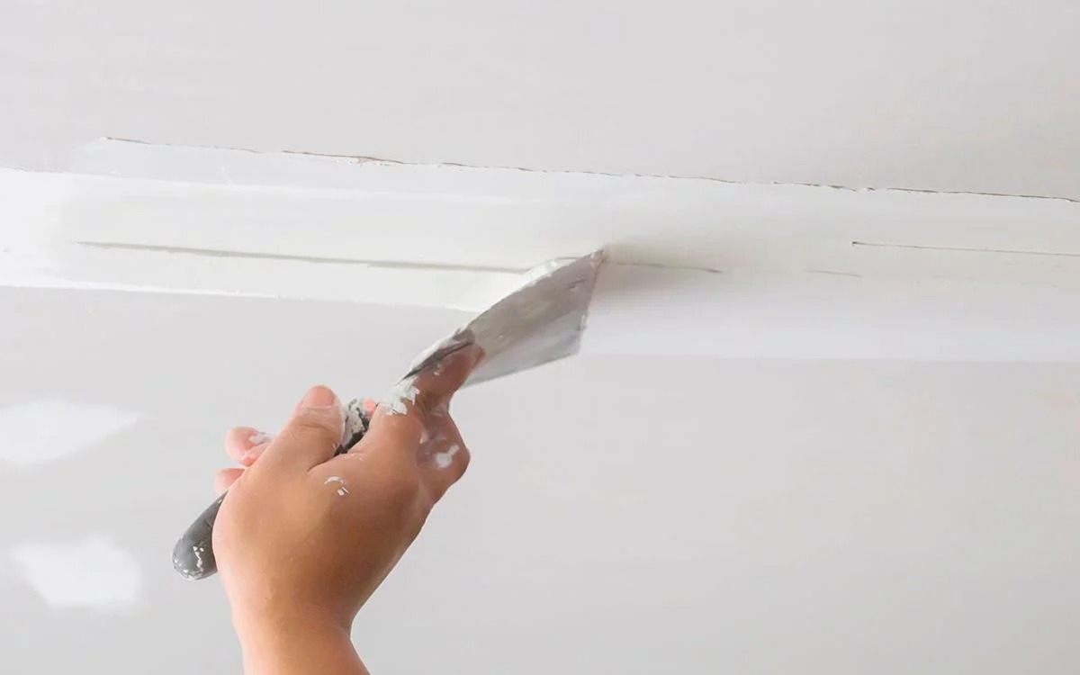 Acabamento de junta de drywall com espátula, superfície lisa e pronta para pintura